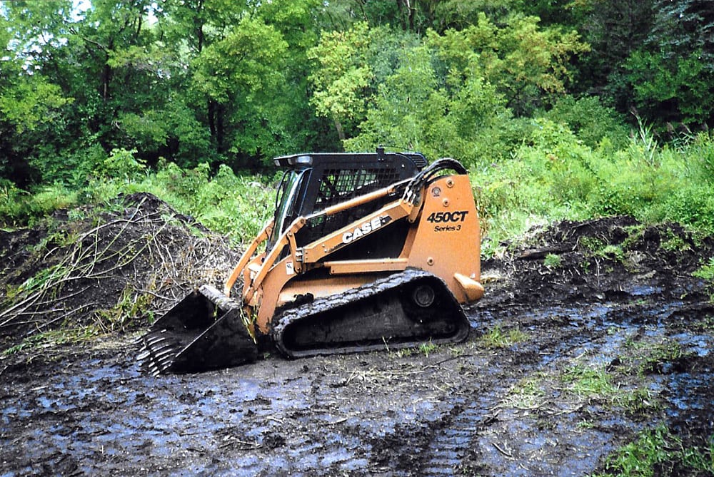 Skid steer loader operating in muddy terrain