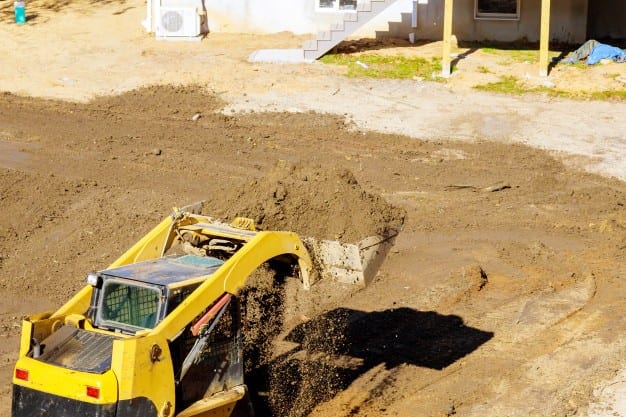 Yellow excavator moving dirt at construction site